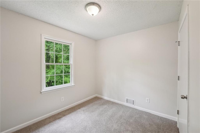 spare room with a textured ceiling, carpet flooring, baseboards, and visible vents