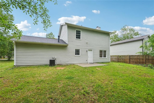 back of property with a yard, a chimney, a patio, and fence