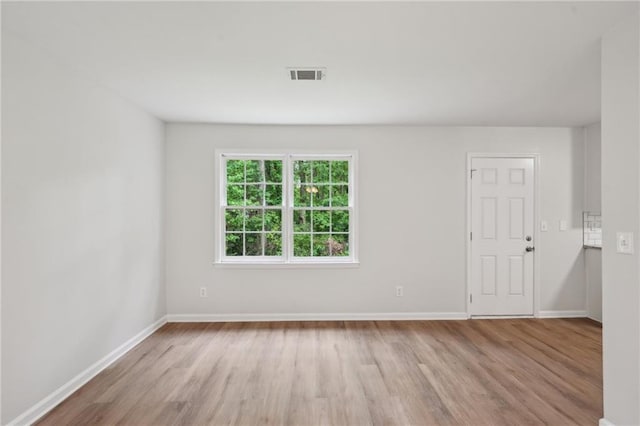 empty room featuring baseboards, wood finished floors, and visible vents