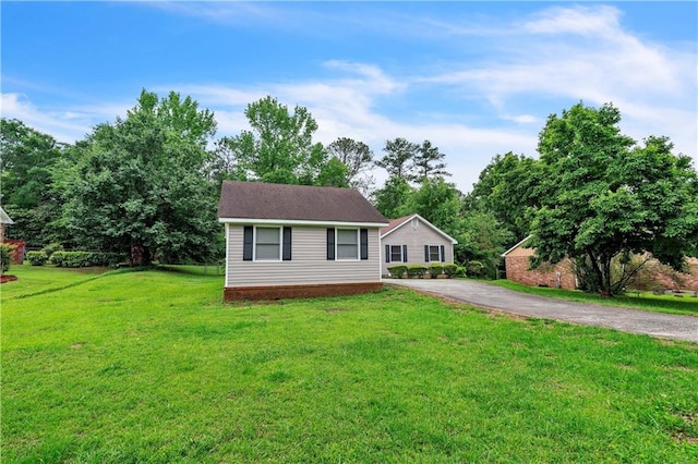 view of front of home with asphalt driveway and a front lawn