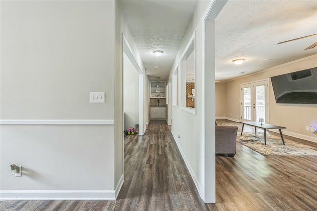 corridor with wood finished floors, baseboards, and a textured ceiling
