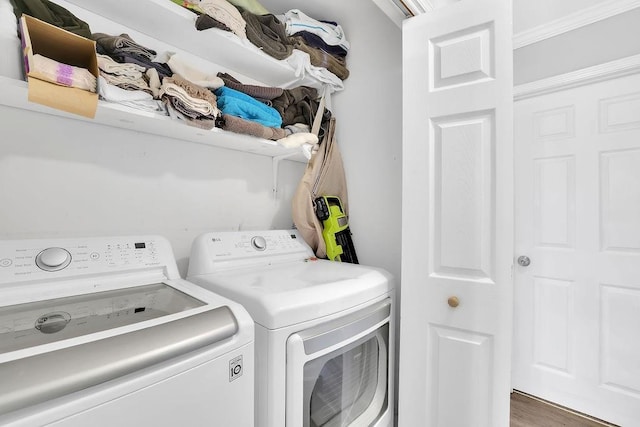 clothes washing area with washing machine and dryer, crown molding, and dark wood-type flooring