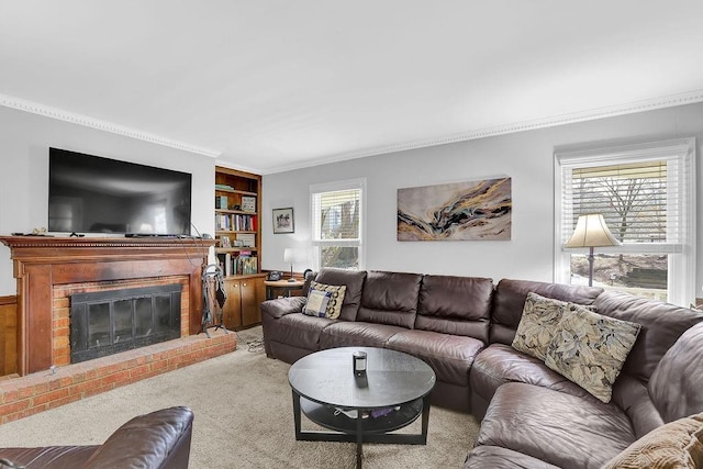 carpeted living room with built in shelves, a brick fireplace, a healthy amount of sunlight, and ornamental molding