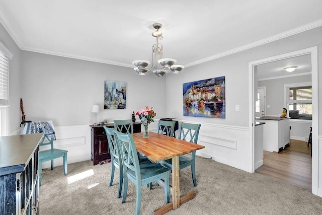 dining room with a chandelier, ornamental molding, and light colored carpet