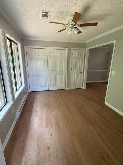 363 Mount Vernon Dr, Calhoun, GA 30701 - unfurnished bedroom with a baseboard radiator, a textured ceiling, wood finished floors, baseboards, and crown molding