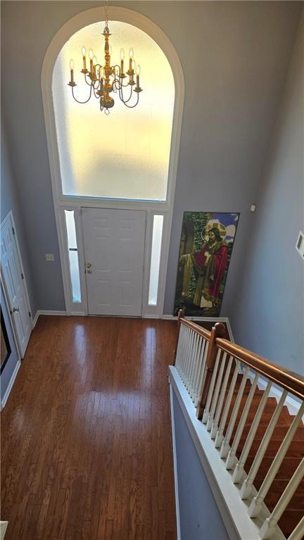 entryway with dark wood-type flooring, a chandelier, and a healthy amount of sunlight