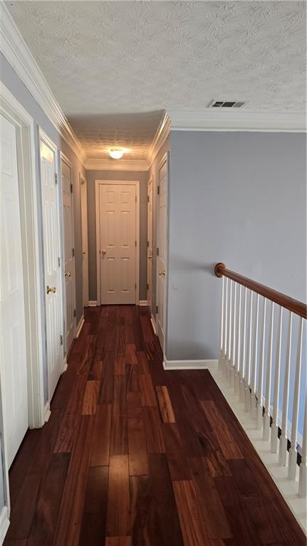 corridor with ornamental molding, dark hardwood / wood-style flooring, and a textured ceiling