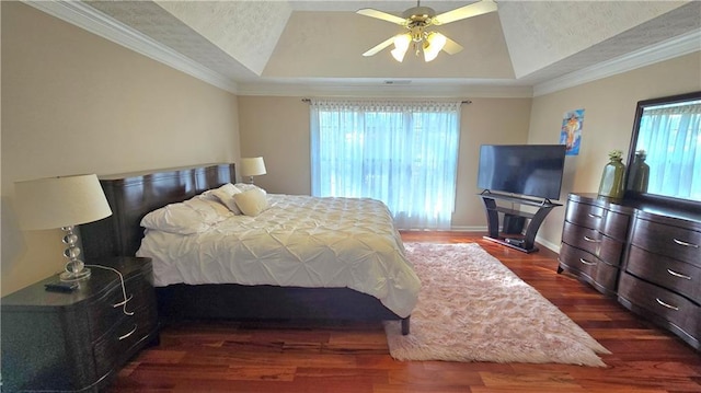 bedroom with crown molding, dark hardwood / wood-style floors, ceiling fan, and a tray ceiling