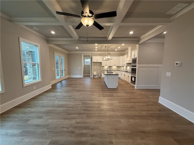 unfurnished living room with coffered ceiling, dark hardwood / wood-style floors, sink, and beamed ceiling