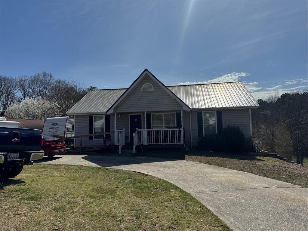 view of front of property with metal roof, a porch, and a front yard