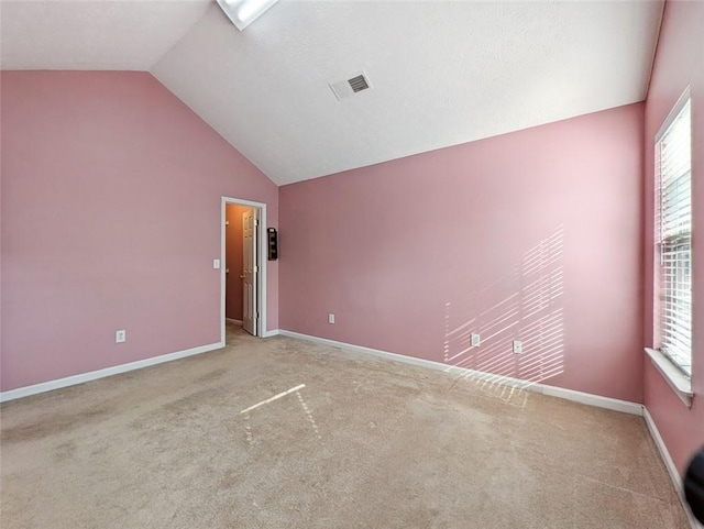 spare room with light carpet and vaulted ceiling