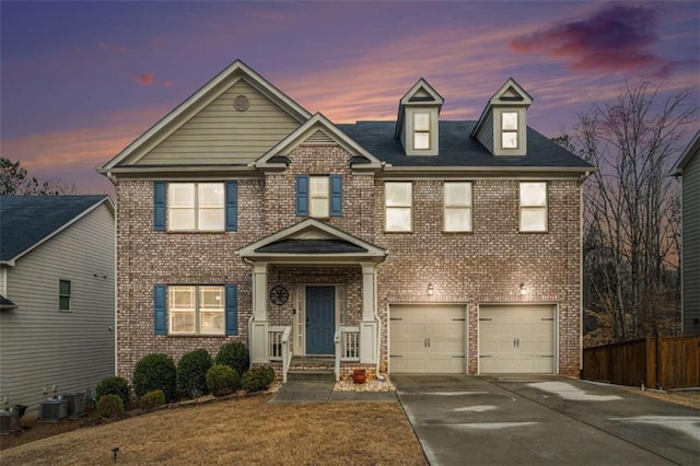 view of front of house with a garage, concrete driveway, brick siding, and fence