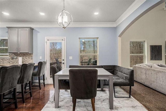 dining space with arched walkways, dark wood-type flooring, ornamental molding, and recessed lighting