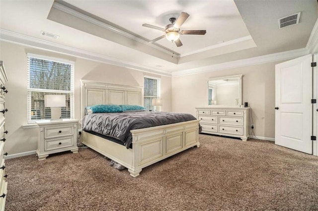 carpeted bedroom with crown molding, a tray ceiling, visible vents, and baseboards