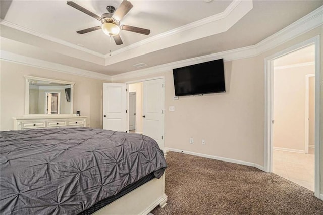 carpeted bedroom with a tray ceiling, crown molding, baseboards, and ceiling fan