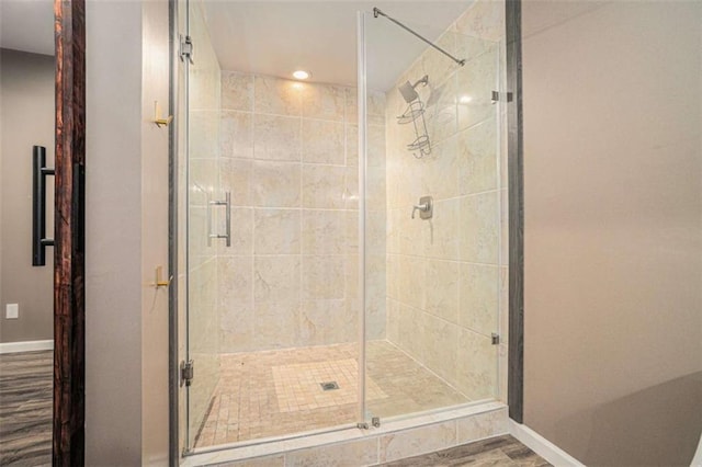 bathroom with a shower stall, baseboards, and wood finished floors