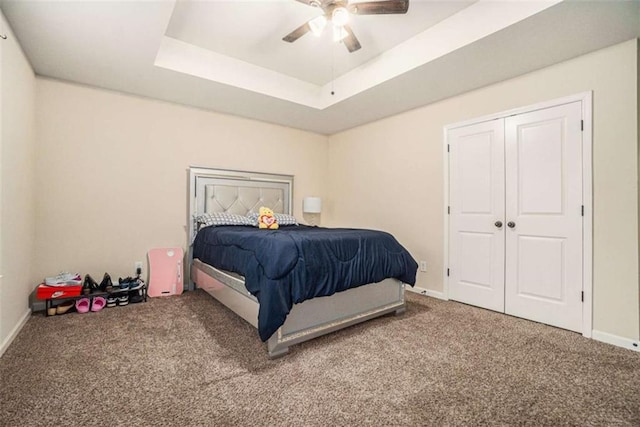 carpeted bedroom with a raised ceiling, ceiling fan, and baseboards