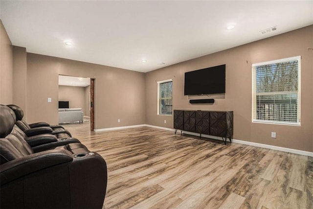 living room featuring visible vents, plenty of natural light, baseboards, and wood finished floors