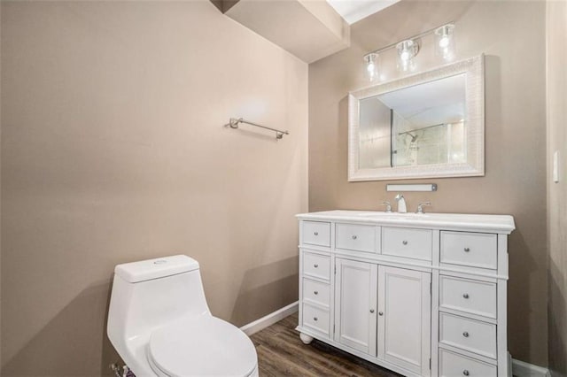 bathroom featuring vanity, wood finished floors, toilet, and baseboards