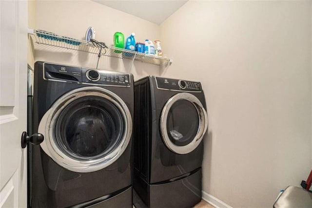 clothes washing area featuring washer and dryer, laundry area, and baseboards