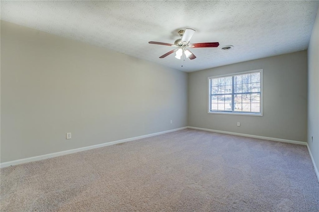 empty room featuring light colored carpet, ceiling fan, and a textured ceiling