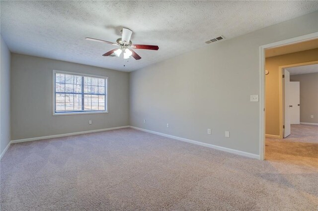 empty room featuring a textured ceiling, light colored carpet, and ceiling fan