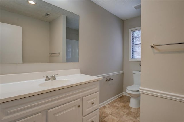 bathroom featuring a textured ceiling, vanity, and toilet