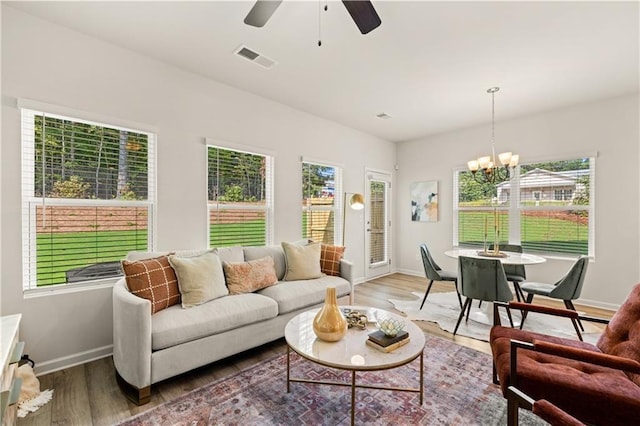 sunroom featuring ceiling fan with notable chandelier