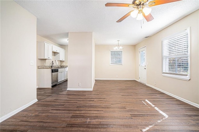 unfurnished living room featuring sink, ceiling fan with notable chandelier, dark hardwood / wood-style flooring, and a textured ceiling