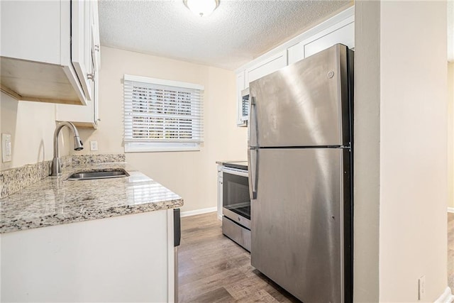 kitchen with light stone countertops, sink, white cabinets, and appliances with stainless steel finishes