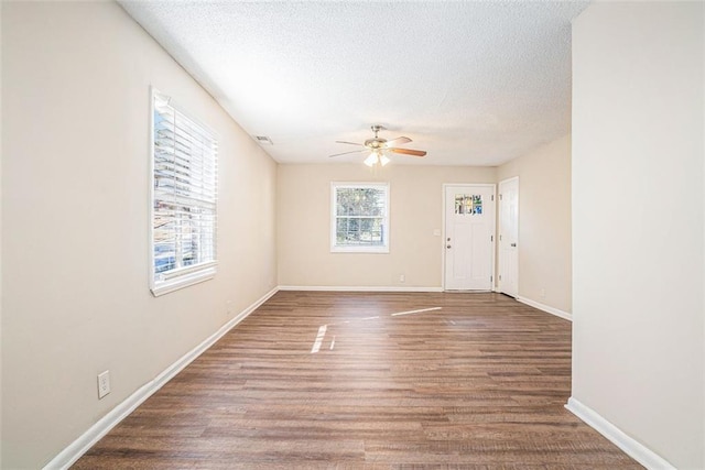 unfurnished room featuring a textured ceiling, hardwood / wood-style flooring, ceiling fan, and a healthy amount of sunlight