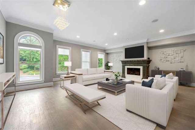 living room with a tile fireplace, light hardwood / wood-style flooring, a chandelier, and ornamental molding