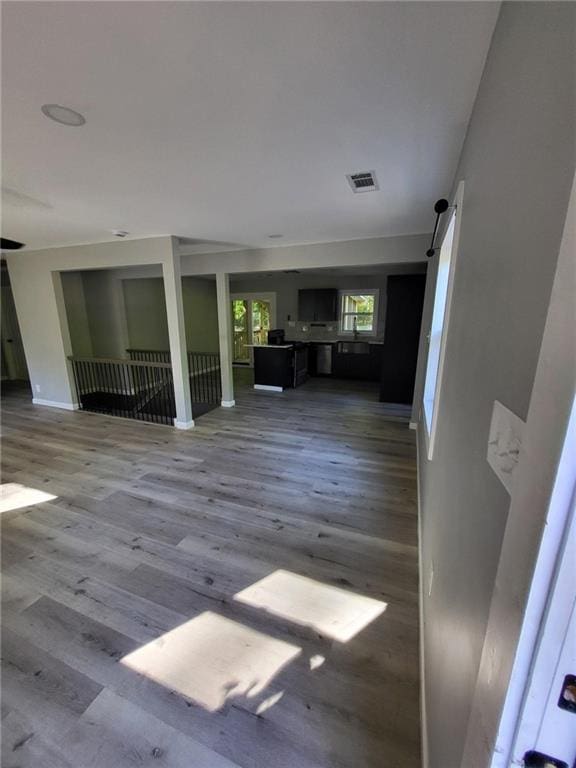 unfurnished living room featuring baseboards, a barn door, visible vents, and wood finished floors