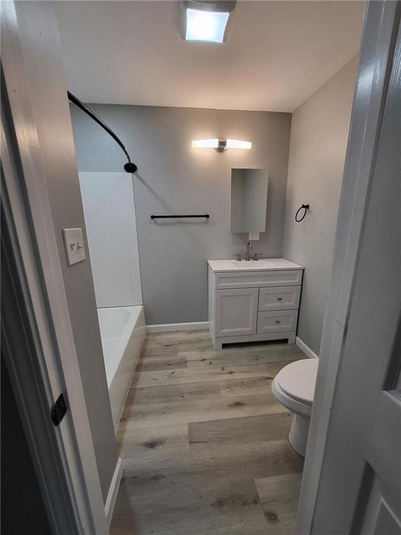 full bath with toilet, baseboards, wood finished floors, and vanity