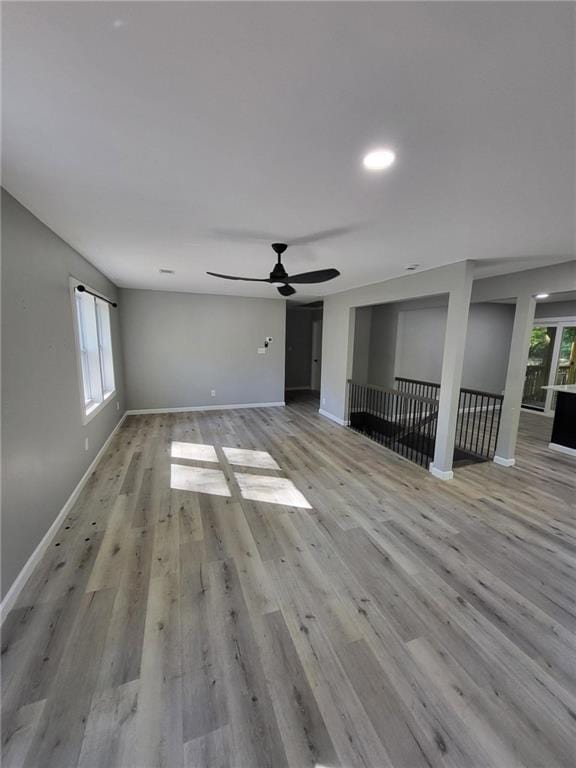 unfurnished living room with baseboards, wood finished floors, and a ceiling fan