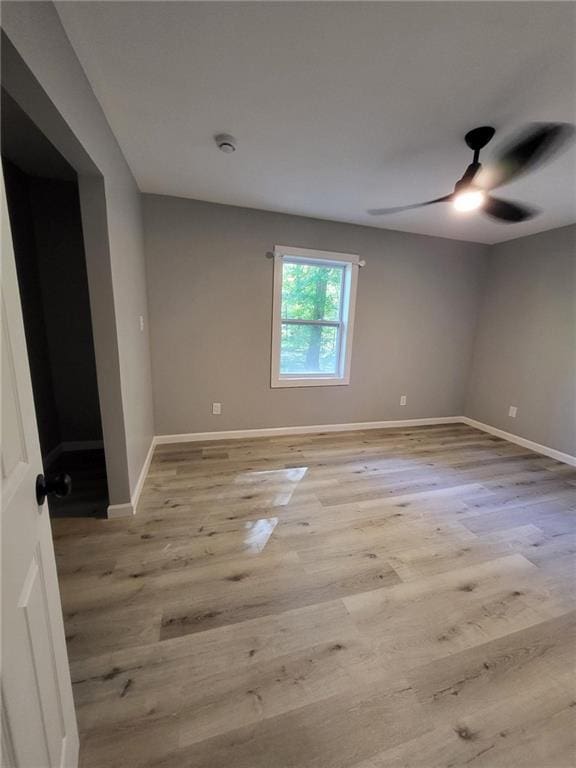 unfurnished room with light wood-style floors, baseboards, and a ceiling fan