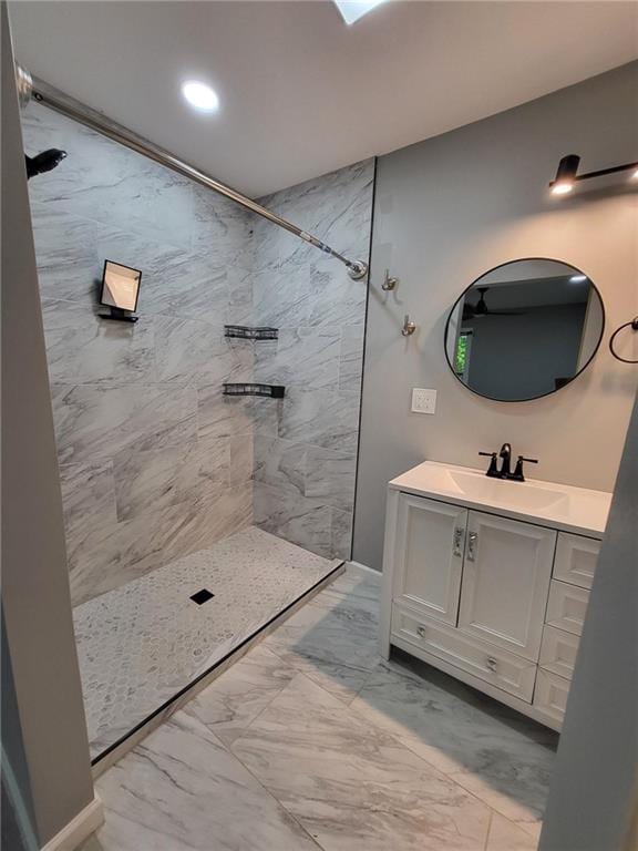 full bath featuring marble finish floor, tiled shower, and vanity