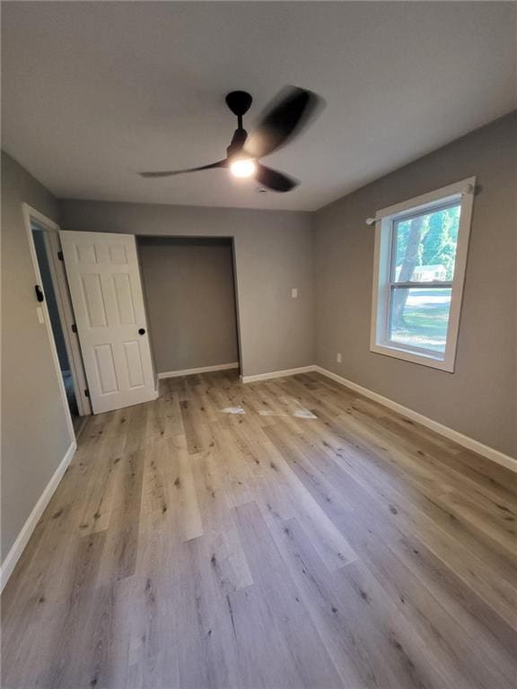 unfurnished bedroom with baseboards, a closet, a ceiling fan, and wood finished floors
