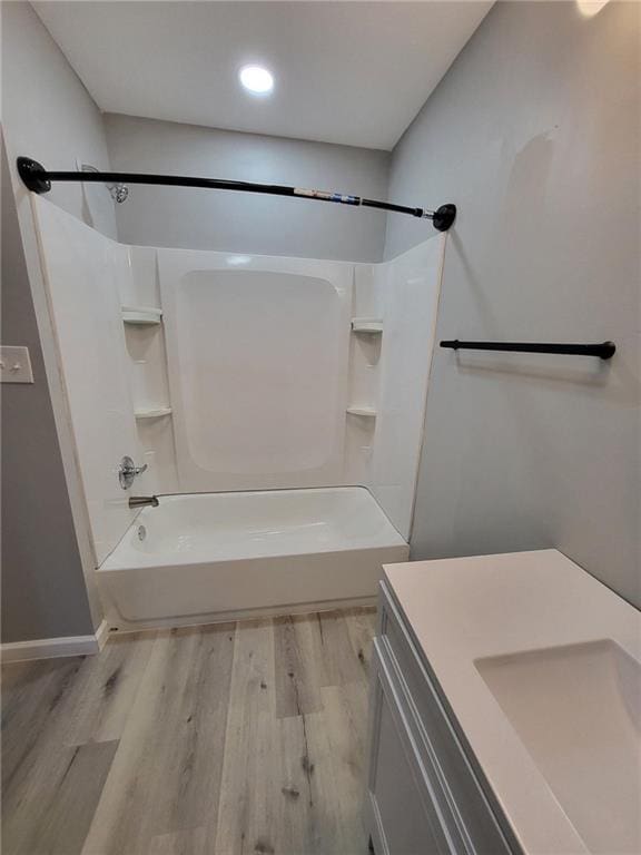 bathroom with wood finished floors, vanity, recessed lighting, washtub / shower combination, and baseboards