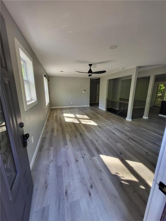 unfurnished living room with ceiling fan, baseboards, a healthy amount of sunlight, and wood finished floors