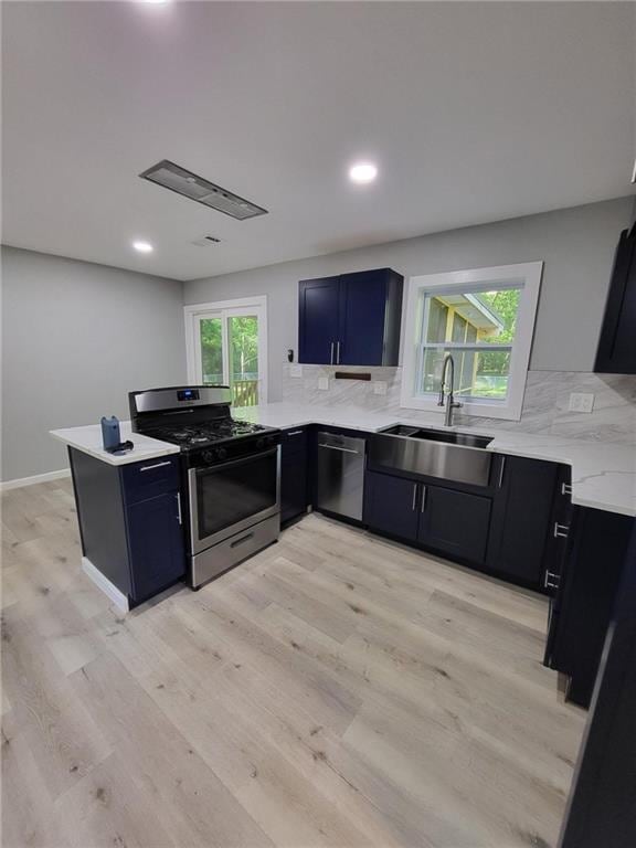 kitchen with a peninsula, appliances with stainless steel finishes, tasteful backsplash, and a sink