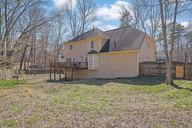 rear view of property featuring a yard, roof with shingles, fence, and a wooden deck