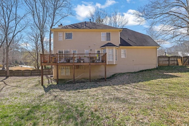 rear view of property featuring a yard, a chimney, fence, and a wooden deck