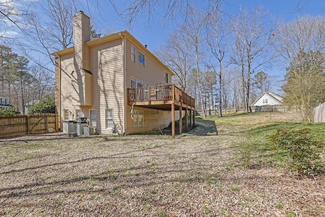 rear view of property featuring fence, a chimney, a wooden deck, and central air condition unit