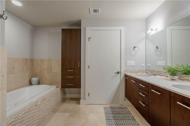 bathroom featuring vanity, tile patterned flooring, and tiled bath