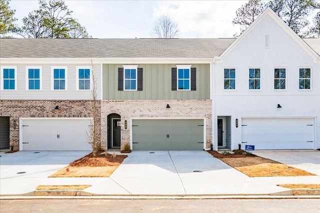 townhome / multi-family property featuring a garage, brick siding, and driveway