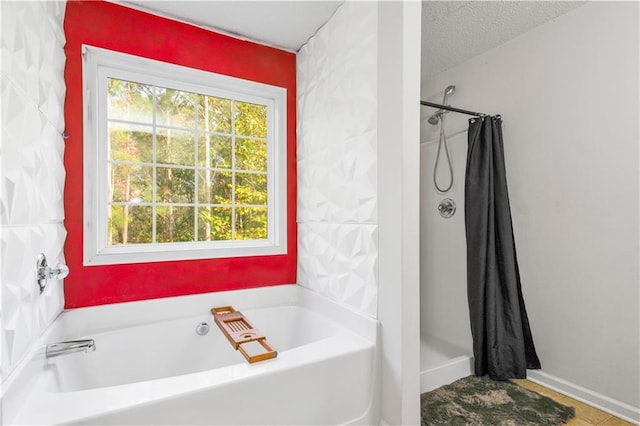 bathroom with a textured ceiling and separate shower and tub