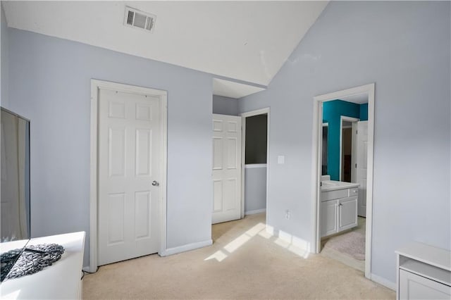 bedroom featuring vaulted ceiling, light carpet, and ensuite bathroom