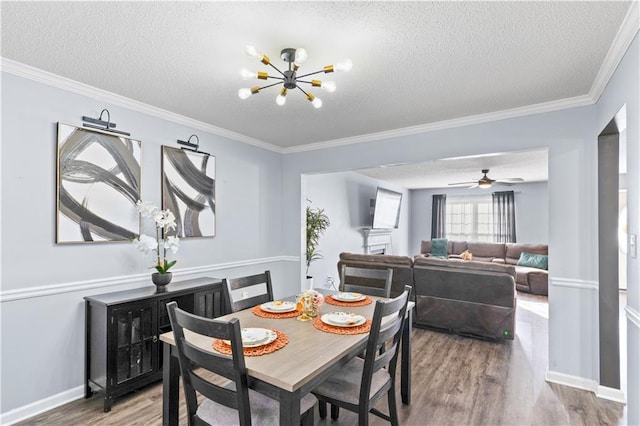 dining space featuring wood-type flooring, a textured ceiling, ceiling fan with notable chandelier, and ornamental molding