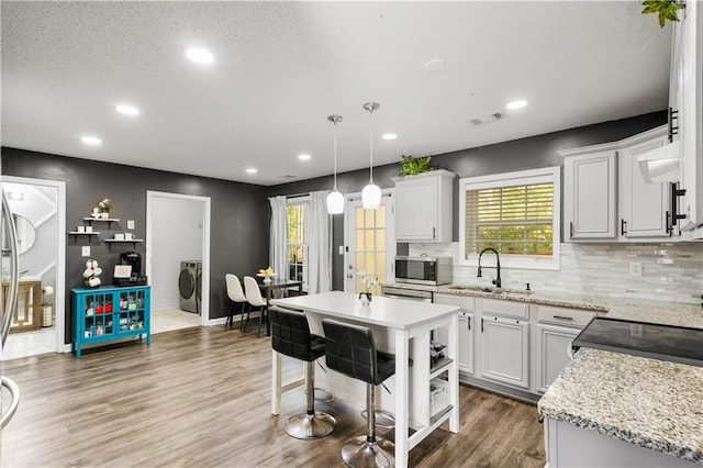 kitchen featuring white cabinetry, washer / dryer, a center island, and hardwood / wood-style floors